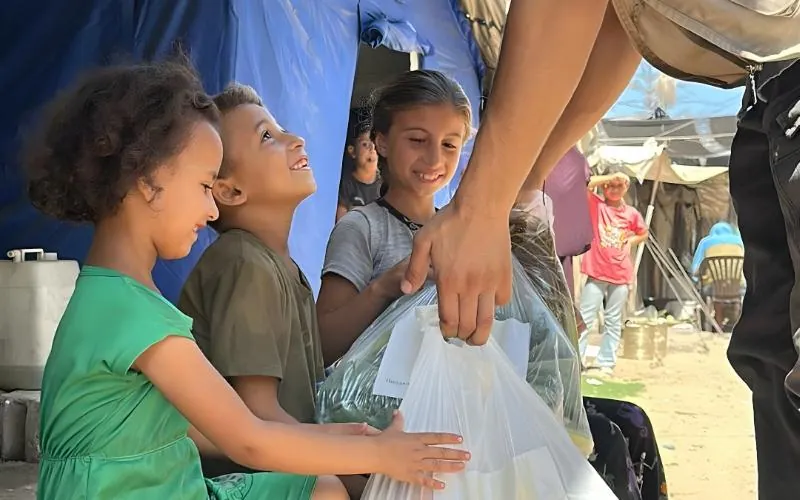 Enfants recevant un colis d’aide lors d’une distribution humanitaire de l’association Eilmy à Gaza